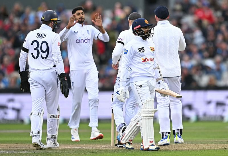 Sri Lanka’s captain Dhananjaya de Silva walks back to the pavilion after losing his wicket for 74 runs to a catch, off the bowling of England’s Shoaib Bashir (2L) on day one of the first Test cricket match between England and Sri Lanka at Old Trafford cricket ground in Manchester, north-west England on 21 August 2024